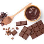 Dark chocolate cream and cocoa powder in wooden spoon with cacao beans isolated on white background. Top view. Flat lay.