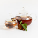 Chaga mushroom infusion isolated on a white background. Healthy chaga tea in a glass teapot and bowl. Side view.